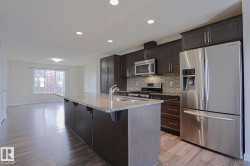 Kitchen featuring dark wood-finish cabinetry, stainless steel appliances, a tiled backsplash, and an island with a light-toned countertop - 