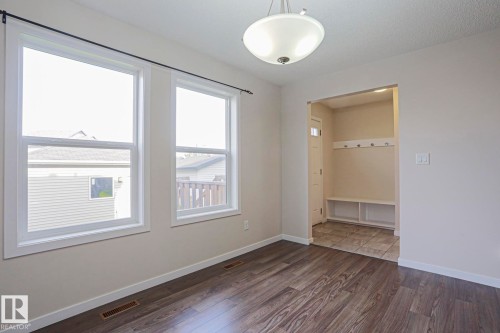 Wood-finish flooring throughout, featuring a built-in entry bench with coat hooks, two bright windows, and a semi-flush mount ceiling light - 308 Watt Boulevard Sw, Edmonton, AB - Indoor Photo Showing Other Room