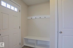 Entryway mudroom with a built-in bench, storage cubbies, and wall-mounted coat hooks - 