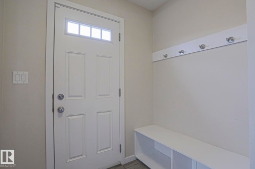 Entryway featuring a white paneled door with transom window, light-toned walls, built-in storage bench, and wall-mounted coat hooks - 308 Watt Boulevard Sw, Edmonton, AB - Indoor Photo Showing Other Room