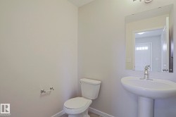 Clean and bright half bathroom featuring a pedestal sink with chrome faucet, a two-piece toilet with closed lid, and neutral wall finishes - 