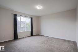 Neutral wall paint, textured carpeting, large window with white trim, and a ceiling-mounted light fixture - 