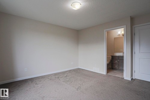 Carpeted room with a flush-mount ceiling light and a white paneled door - 308 Watt Boulevard Sw, Edmonton, AB - Indoor Photo Showing Other Room