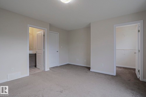 Plush carpet flooring, a walk-in closet with shelving, a bathroom with vanity, and a flush mount ceiling light - 308 Watt Boulevard Sw, Edmonton, AB - Indoor Photo Showing Other Room
