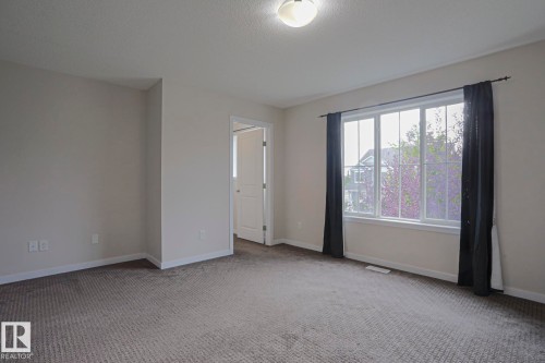 Neutral wall tones, gray patterned carpet, and a large window with white trim - 308 Watt Boulevard Sw, Edmonton, AB - Indoor Photo Showing Other Room