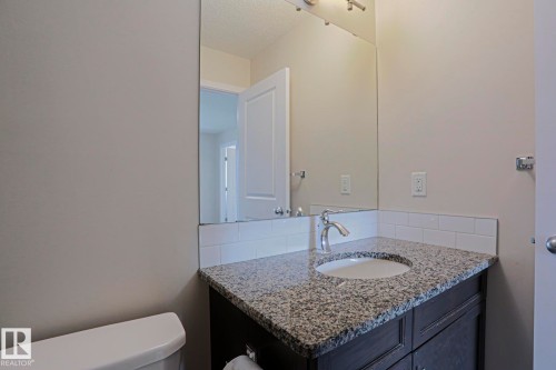 Vanity with a granite-style countertop, undermount sink, and chrome faucet - 308 Watt Boulevard Sw, Edmonton, AB - Indoor Photo Showing Bathroom