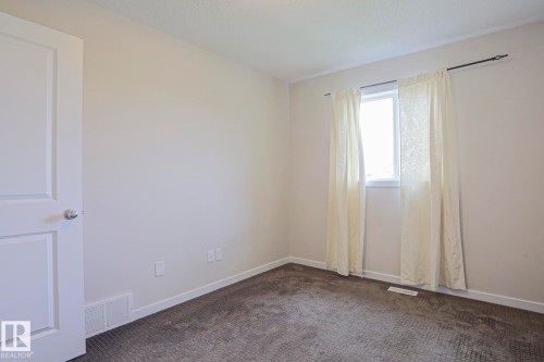 Neutral wall paint, white trim, gray carpet, white interior door, and a single window - 308 Watt Boulevard Sw, Edmonton, AB - Indoor Photo Showing Other Room