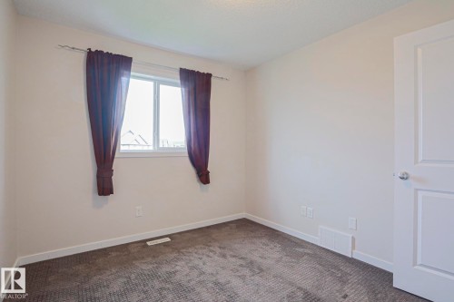 Recessed window with white trim, gray patterned carpeting, white wall paint, and a white two-panel door - 308 Watt Boulevard Sw, Edmonton, AB - Indoor Photo Showing Other Room