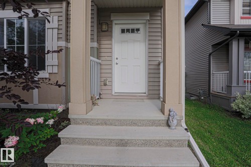 Entry with concrete stairs, white railing, and a paneled door featuring a window - 308 Watt Boulevard Sw, Edmonton, AB - Outdoor