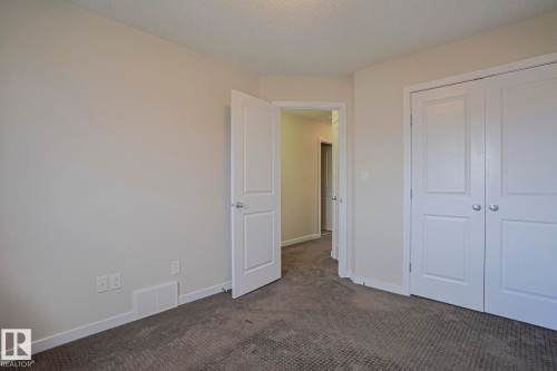 Neutral tone wall finish, textured ceiling, paneled door, bi-fold closet doors, and carpet flooring - 308 Watt Boulevard Sw, Edmonton, AB - Indoor Photo Showing Other Room