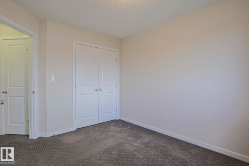 Neutral wall color, textured carpeting, white trim, and white paneled doors - 308 Watt Boulevard Sw, Edmonton, AB - Indoor Photo Showing Other Room