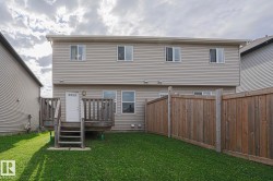 Two-story home with vinyl siding exterior, multiple windows across the upper level, and a spacious backyard featuring a manicured lawn - 