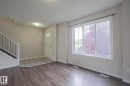 Wood-finish flooring, tiled entry, white interior door with lites, staircase with white newel post and dark balusters, and a large window with white framing - 308 Watt Boulevard Sw, Edmonton, AB  - Indoor Photo Showing Other Room 