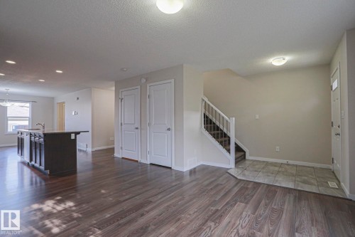 Open-concept living area featuring wood-finish flooring, recessed lighting, and a kitchen island with integrated sink - 308 Watt Boulevard Sw, Edmonton, AB - Indoor