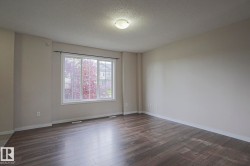 Spacious room featuring wood-finish flooring, a large multi-pane window, and neutral wall tones - 
