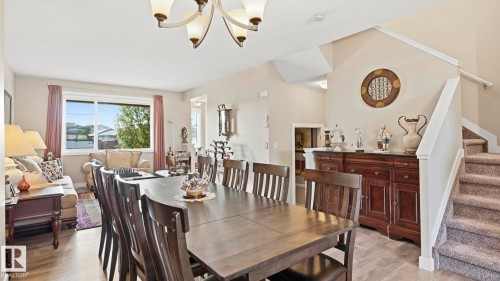Open-concept living space featuring a dining area with a chandelier, wood-finish flooring, and a large window - 731 36 Street Sw, Edmonton, AB - Indoor Photo Showing Dining Room