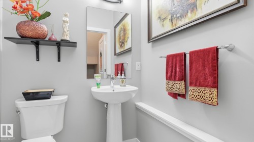 Pedestal sink with chrome faucet, framed mirror, and wall-mounted light fixture - 731 36 Street Sw, Edmonton, AB - Indoor Photo Showing Bathroom