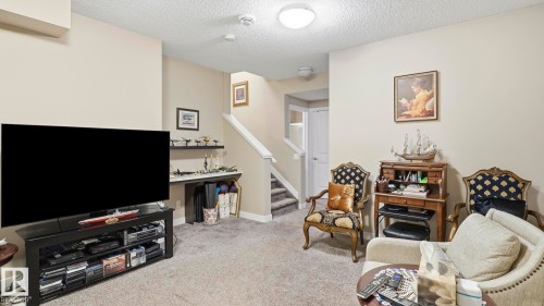 Carpeted living area featuring light neutral wall paint and a textured ceiling - 731 36 Street Sw, Edmonton, AB - Indoor