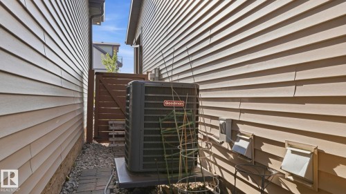Side yard with gravel and paver stone pathway, featuring a Goodman HVAC unit and light-colored horizontal siding - 731 36 Street Sw, Edmonton, AB - Outdoor