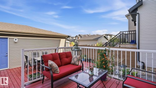 Spacious outdoor deck featuring red-stained wood-finish flooring, white railing, and a vibrant blue door - 731 36 Street Sw, Edmonton, AB - Outdoor With Deck Patio Veranda With Exterior