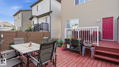 Spacious outdoor deck featuring red-stained wood flooring, white railings, and a vibrant red exterior door - 731 36 Street Sw, Edmonton, AB - Outdoor With Deck Patio Veranda With Exterior