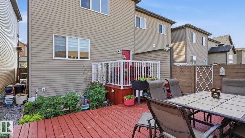 Rear exterior with a wood deck, white railing, and a red entry door - 731 36 Street Sw, Edmonton, AB - Outdoor With Deck Patio Veranda With Exterior