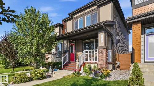 Contemporary two-story exterior featuring a red entry door, a brick and siding facade, and a covered porch with white railings - 731 36 Street Sw, Edmonton, AB - Outdoor With Facade