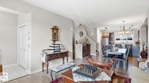 Open-concept living space featuring wood-finish flooring, a contemporary kitchen with stainless steel appliances, and a dining area illuminated by pendant lighting - 731 36 Street Sw, Edmonton, AB - Indoor