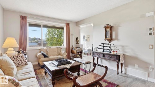 Open-concept living area with light gray wall paint and wood-finish flooring - 731 36 Street Sw, Edmonton, AB - Indoor Photo Showing Living Room