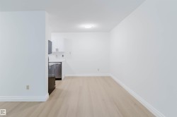Recessed kitchen area with white cabinetry, stainless steel dishwasher, and refrigerator - 