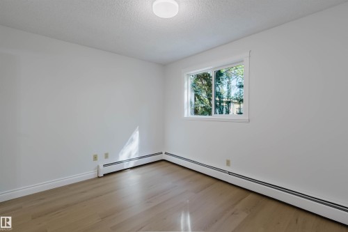 Wood-finish flooring, white walls, and a window with white trim - #106 10520 80 Av Nw, Edmonton, AB - Indoor Photo Showing Other Room