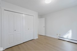 Light wood-finish flooring, white walls, white bi-fold closet doors, white baseboards, and a flush-mount ceiling light - 