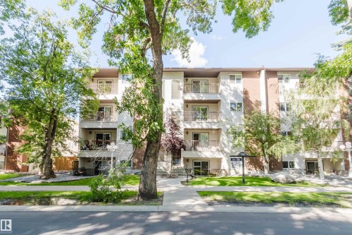 Multi-story exterior with individual balconies, brick facade accents, and mature trees - #106 10520 80 Av Nw, Edmonton, AB - Outdoor With Balcony With Facade