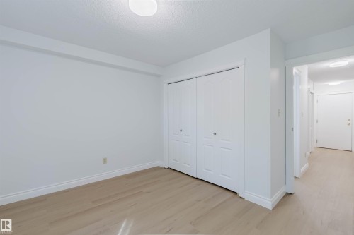 Light wood-finish flooring, white walls, and a built-in closet with bifold doors - #106 10520 80 Av Nw, Edmonton, AB - Indoor Photo Showing Other Room