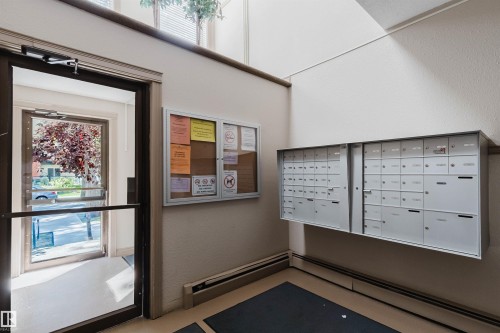 Secure mailboxes within an entry vestibule featuring a glass-paneled door - #106 10520 80 Av Nw, Edmonton, AB - Indoor Photo Showing Other Room