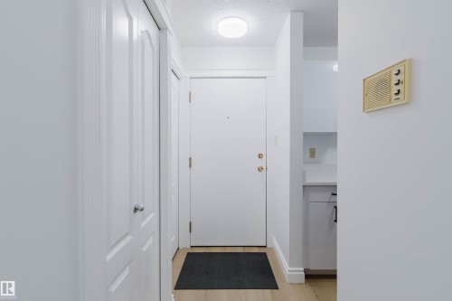 Light wood-finish flooring with white baseboards - #106 10520 80 Av Nw, Edmonton, AB - Indoor Photo Showing Other Room