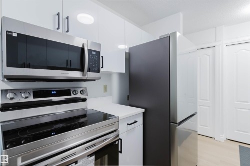 Stainless steel range, microwave, and refrigerator complement white cabinetry with dark hardware - #106 10520 80 Av Nw, Edmonton, AB - Indoor Photo Showing Kitchen With Stainless Steel Kitchen