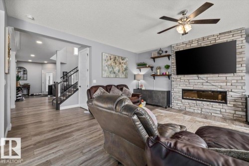 Living area with a stone-clad fireplace and integrated media space - 5203 23A Avenue Sw, Edmonton, AB - Indoor Photo Showing Living Room With Fireplace