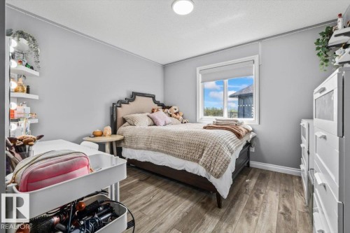 Wood-finish flooring, white trim, recessed ceiling light, window with roller shade, and built-in floating shelves - 5203 23A Avenue Sw, Edmonton, AB - Indoor Photo Showing Bedroom