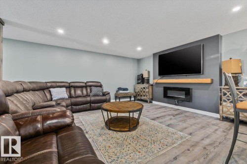 Recessed ceiling lighting, wood-finish flooring, built-in electric fireplace, and a floating wood mantel - 5203 23A Avenue Sw, Edmonton, AB - Indoor With Fireplace