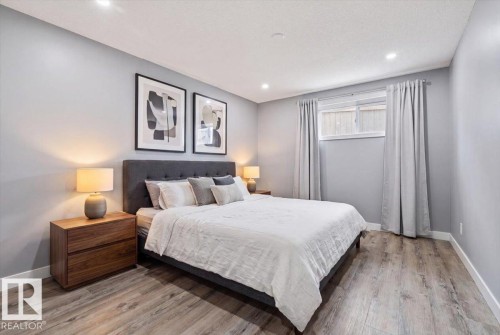 Wood-finish flooring, recessed ceiling lighting, light gray wall color, and a window with curtains - 5203 23A Avenue Sw, Edmonton, AB - Indoor Photo Showing Bedroom