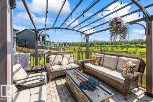 Wood-finish deck with a black metal pergola, dark wood railing, and integrated string lighting - 5203 23A Avenue Sw, Edmonton, AB - Outdoor With Deck Patio Veranda