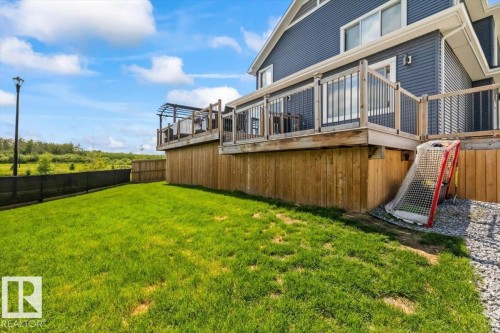 Spacious backyard with a vibrant green lawn, elevated wood deck featuring a pergola, and a private wood fence - 5203 23A Avenue Sw, Edmonton, AB - Outdoor With Deck Patio Veranda