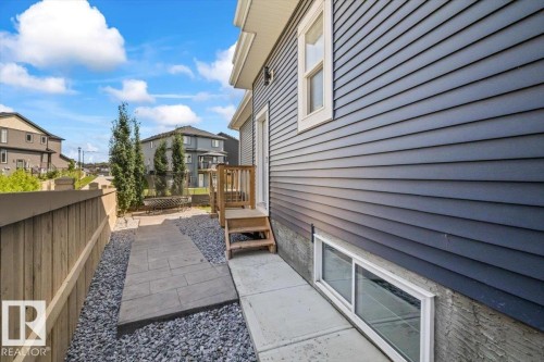 Blue horizontal siding, a private wooden fence, and a stone-paved pathway - 5203 23A Avenue Sw, Edmonton, AB - Outdoor With Exterior