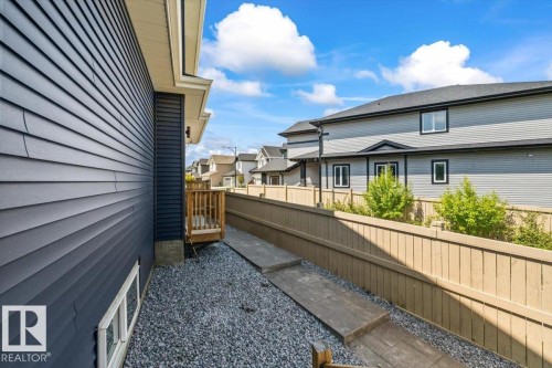 Side yard featuring a gravel surface, wood privacy fencing, and a concrete pathway - 5203 23A Avenue Sw, Edmonton, AB - Outdoor