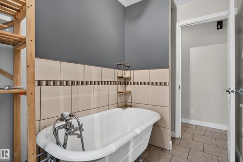 Freestanding clawfoot bathtub with chrome fixtures, complemented by a tile wainscoting featuring a decorative border - 11549 88 Street Nw, Edmonton, AB - Indoor Photo Showing Bathroom