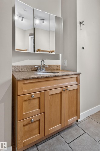 Wood-finish vanity with chrome hardware, an integrated sink, a speckled countertop, and a mirrored medicine cabinet - 11549 88 Street Nw, Edmonton, AB - Indoor Photo Showing Bathroom