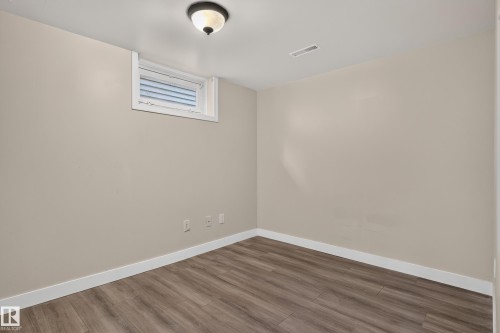 Wood-finish flooring with white trim, a single window with white framing, and a ceiling-mounted light fixture - 11549 88 Street Nw, Edmonton, AB - Indoor Photo Showing Other Room