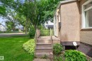Exterior featuring stucco siding, white-framed windows, and a wooden entry deck with railings - 11549 88 Street Nw, Edmonton, AB  - Outdoor With Exterior 
