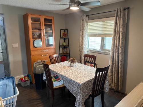 Recessed window with blinds and drapes, wood-finish flooring, built-in display cabinetry, and a ceiling fan with integrated lighting - 7065 Cardinal Way Sw, Edmonton, AB - Indoor Photo Showing Dining Room